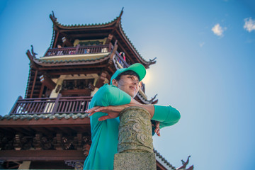 Fototapeta na wymiar Beautiful girl near the Chinese pagoda, Girl in a turquoise sweater and cap