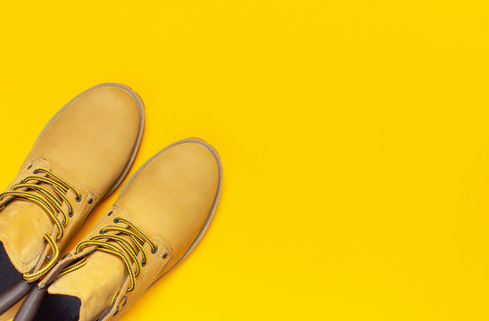 Fashionable concept. Yellow men's work boots from natural nubuck leather on bright yellow background top view flat lay with copy space. Trendy casual shoes, youth style. Advertising sale shop
