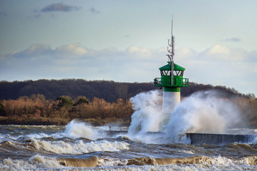 lighthouse during storm in splashing spray in Travemuende, tourist destination on the Baltic Sea in the Luebeck bay, copy space © Maren Winter