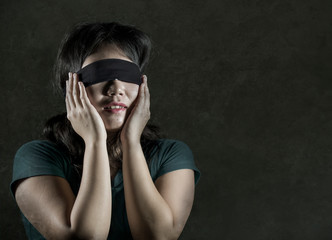 young scared and blindfolded Asian Korean teenager girl lost and confused playing dangerous internet viral challenge isolated on dark background