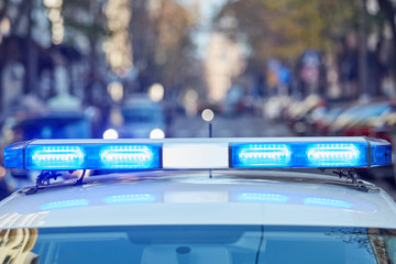 Police car with blue lights on the crime scene in traffic / urban environment.