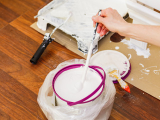 Person mixing white paint in bucket.