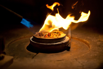melting golden metal in furnace with fire for making jewelry