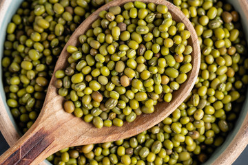 fresh mung beans in ceramic dishes against a dark stone background