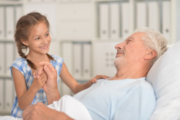 Portrait of cute girl visiting sick grandgfather