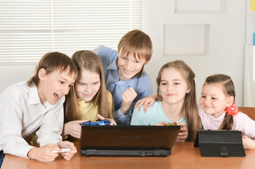 Portrait of funny boys and girls playing computer game together at the table at home