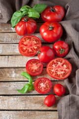 Colorful tomatoes of different sizes and  fresh basil leaves