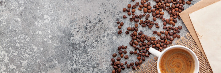 Close up coffee cup and beans, old paper on stone table top view. Panoramic copy space.