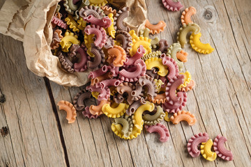 Raw colored pasta scattered on the wooden old table