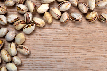 Heap of salted pistachio nuts on wooden board. Top view.