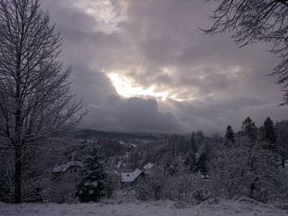 Obraz premium A sunrise on a winter sunrise. In the sky there is a stormy cloud of snow and rays of the sun