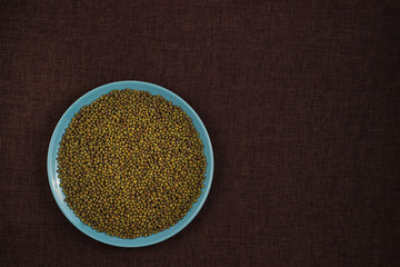 Organic mung beans on blue ceramic dish over canvas background