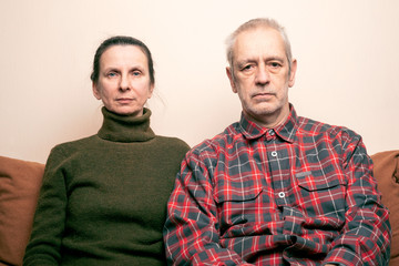 Dramatic portrait of sad and depressed adult woman and man sit on a sofa and  looking into space...