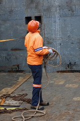 A worker readying lines to secure cargo in a ship cargo hold