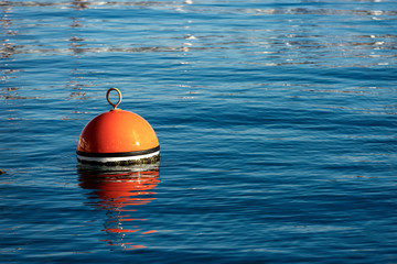 Red and orange mooring buoy in the sea - obrazy, fototapety, plakaty