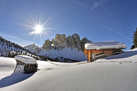 Winterlandschaft mit Berghütten und Sonne | UNESCO Dolomiten