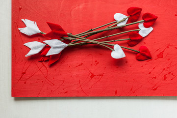 Valentines day twig arrows on red wooden background. Handmade cupid's arrows.