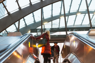 The happy young friends going to the escalator in the subway