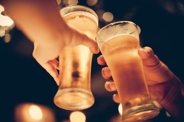 glass of cold beer bottoms up with beautiful bokeh, friends drink beer together, dark tone