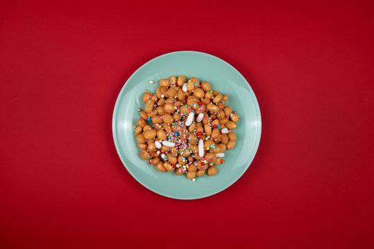 piatto di  di tipici dolci napoletani Struffoli su un fondo rosso