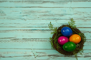 Osternest mit bunten Eiern auf blauem Holzhintergrund