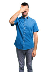 Handsome man with blue shirt covering eyes by hands