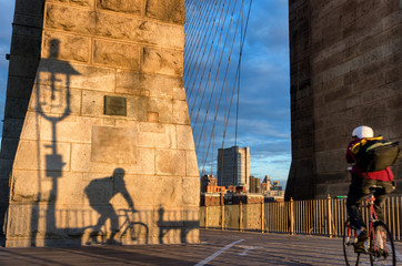 Bicyclist on Brooklyn Bridge during sunrise in New York. USA