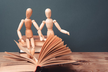 Two wooden man reading a book.