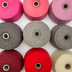 multi-colored bobbins of yarn on a white background.