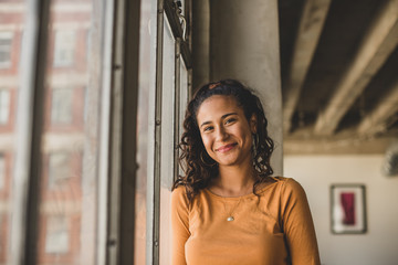 Portrait of smiling woman standing by window