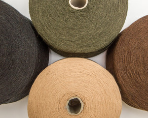 multi-colored bobbins of yarn on a white background.