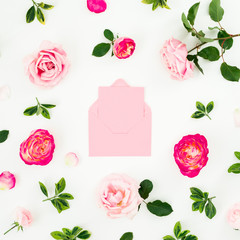 Floral composition of pink roses flowers and pink envelope on white background. Flat lay, top view.