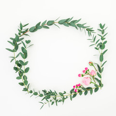 Wreath flower frame of pink roses flowers and eucalyptus branches on white background. Flat lay, top view
