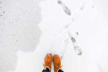 Top view of yellow shoes / boots standing on the ice near the sea. Winter season.