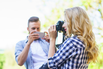 Man and woman taking photos with a camera and a smartphone.