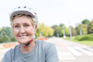 Smiling senior woman wearing cycling helmet in park