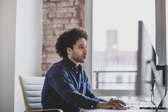Side view of businessman working on desktop computer in office