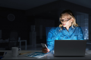 Beautiful blonde in dark office working on laptop and getting net access