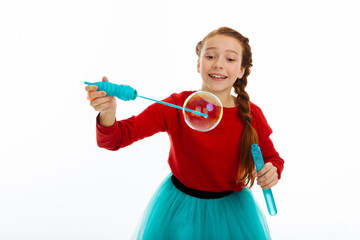 Joyful happy girl playing with soap bubbles