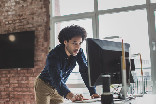 Male african american business executive standing and working on a desktop computer