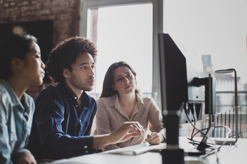 Coworkers looking at a desktop computer together