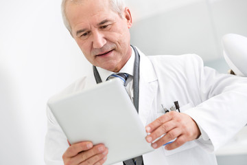 Doctor reading medical report on digital tablet at dental clinic
