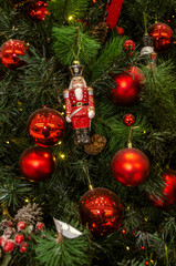 Christmas background from natural and artificial pine branches with an old Nutcracker toy, figurines, cones and red balls

