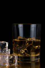 glass of whiskey and ice isolated on black background