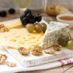 Appetizers of various types of cheese, grapes, nuts and honey, served with white and red wine. Rustic style.