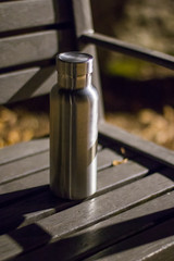 an insulated stainless steel bottle on the bench in the night forest