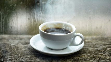 Wet glass window and cup of hot coffee. Autumn cloudy weather better with caffeine drink. Enjoying coffee on rainy day. Coffee time on rainy day. Fresh brewed coffee in white cup or mug on windowsill