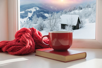 cup with a hot drink on the windowsill in the background of a winter city. Focus on the edge of the...