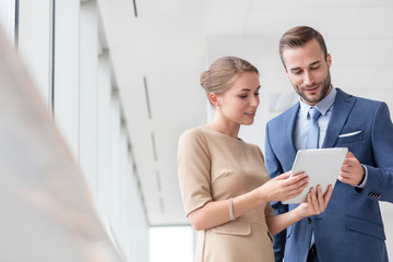 Confident young colleagues discussing over digital tablet at new office