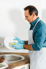 handsome mature man washing dishes in kitchen